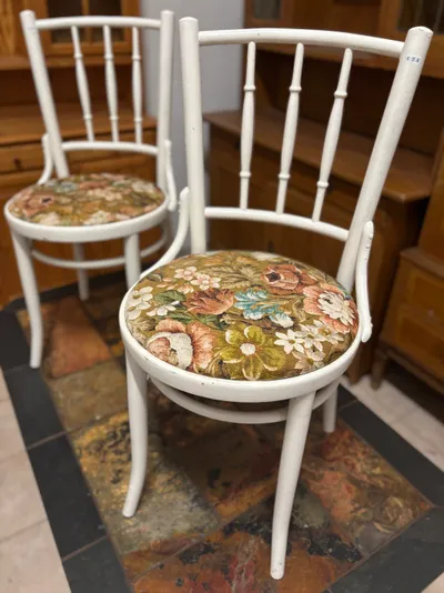 Pāris baltu koka krēslu ar atzveltnēm un apaļiem, ziedu r...
